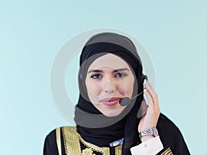 Portrait of muslim woman with headset on cyan background