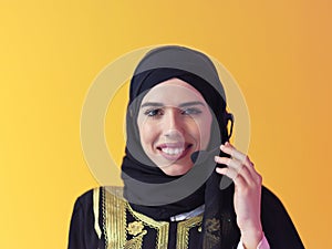 Portrait of muslim woman with headset on yellow background