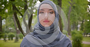 Portrait of muslim woman in hijab watching arrogantly into camera walking in the park.