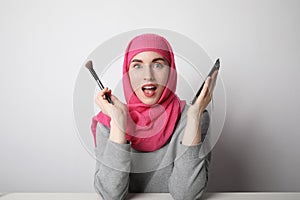 Portrait of a muslim woman wearing a head scarf and doing make-up. Isolated.