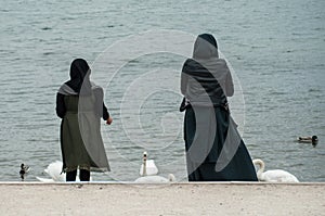 Portrait of muslim women back view gibing bread to the duck and swan in border lake