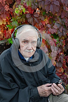 Portrait of a mustachioed Mature man with an attentive and serious face in headphones. An old man is relaxing and listening to