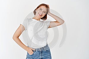 Portrait of natural beauty girl with light make-up, touching short hair and smiling happy, standing in casual t-shirt