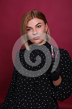 portrait of a natural blonde girl of an eyelash master with blonde hair in a black dress in black disposable gloves in a studio