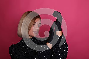 portrait of a natural blonde make-up artist girl with blonde hair in a black dress in black disposable gloves in a studio room,