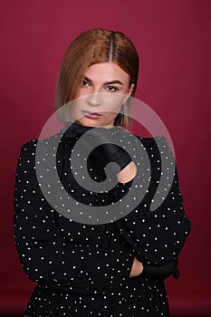 portrait of a natural blonde make-up artist girl with blonde hair in a black dress in black disposable gloves in a studio room,