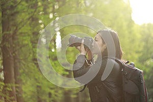 Portrait of a nature photographer covering her face with camera in a spring park