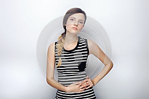 Portrait of naughty young beautiful woman in striped shirt contemptuous looking into camera posing for model tests against studio