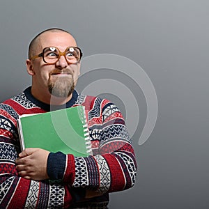 Portrait of a nerd holding book with retro glasses against gray background