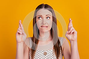 Portrait of nervous lady crossed fingers bite lip look side on yellow background