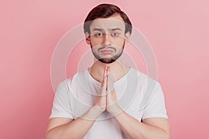 Portrait of nervous upset guy hold palms together cry ask help on pink background