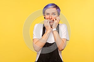 Portrait of nervous worried hipster girl biting nails fingers, looking at camera with anxiety. studio shot