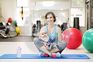 Portrait of new mom on group exercise class in gym. Moms staying active while boding with babies.