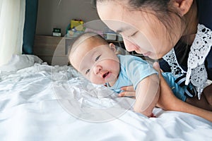 Portrait of a newborn Asian baby boy on the bed , Charming Fat baby 5 month old lies in bed and the doll ,enjoy and happy,soft and