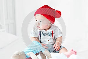 Portrait of a newborn Asian baby, A child wore a suit and a red wool hat sit ting on bedroom, Cute and smilingly photo