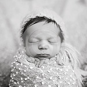 Portrait of newborn baby boy wrapped in popcorn wrap with knitted wool cap on head. Infant sleeping. Newborn baby with beautiful