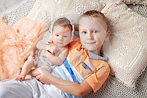 Portrait of newborn baby girl and elder brother. Young boy lying with newborn sister