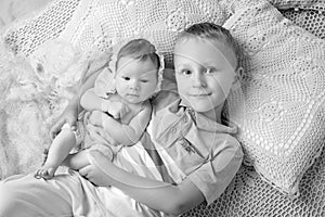 Portrait of newborn baby girl and elder brother. Young boy lying with newborn sister