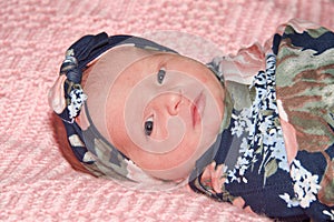 Portrait of a newborn baby girl swaddled laying on pink blanket