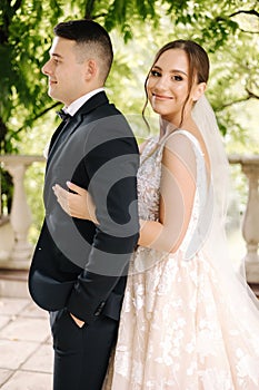 Portrait of newlyweds stand on balcony and dreaming. Handsome groom and beautiful bride on their wedding day