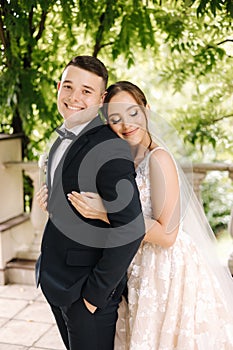 Portrait of newlyweds stand on balcony and dreaming. Handsome groom and beautiful bride on their wedding day