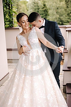 Portrait of newlyweds stand on balcony and dreaming. Handsome groom and beautiful bride on their wedding day