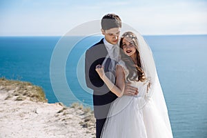 Portrait of newlyweds on wedding day at cliff with beautiful view of ocean