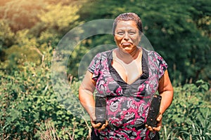 Portrait of a Nicaraguan peasant woman holding bags of plants in rural Masaya Nicaragua. Photo with copy space.
