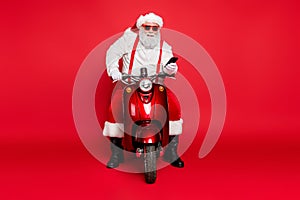 Portrait of nice attractive bearded cheerful cheery Santa wearing cap hat sitting on motor bike using cell taking orders