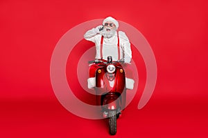 Portrait of nice attractive bearded cheerful funny Santa wearing cap hat riding motor bike talking on phone taking