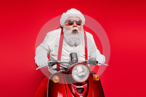 Portrait of nice attractive bearded crazy cheerful cheery funny funky Santa riding motor bike delivering shop orders