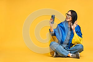 Portrait of nice beautiful lovely glad cheerful woman holding in hands Ukrainian flag having fun isolated over yellow background.