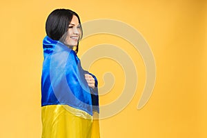 Portrait of nice beautiful lovely glad cheerful woman holding in hands Ukrainian flag having fun isolated over yellow pastel color
