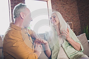 Portrait of nice cheerful couple sitting on sofa talking spending time having fun at modern loft industrial interior