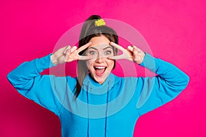 Portrait of nice cheerful girl open mouth smile two arms fingers show v-sign near eye isolated on pink color background