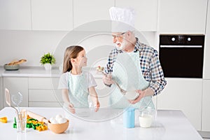 Portrait of nice cheerful kind grey-haired grandparent teaching grandchild cooking homemade domestic natural organic