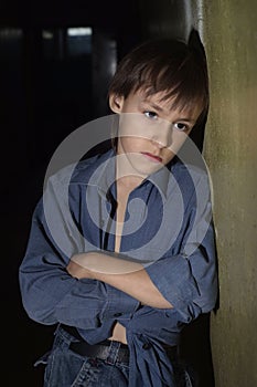 Portrait of nice sad kid sitting in a dark room