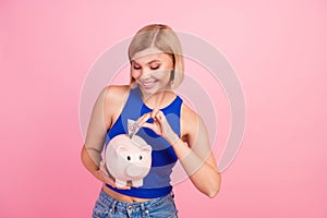 Portrait of nice young girl money bank pig empty space wear blue top isolated on pink color background