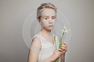 Portrait of nice young woman with blonde updo hair and white flowers in hands on white background