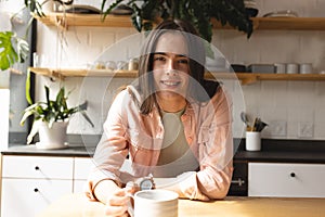 Portrait of non-binary trans woman with coffee cup smiling in the kitchen at home photo