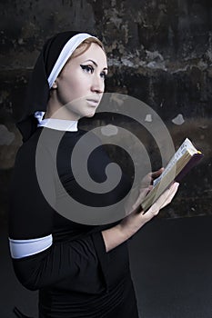 portrait of a nun in black clothes reading the bible and using a rose petal as a bookmark