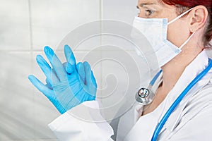 Portrait of a nurse or doctor putting on her surgical gloves to protect herself