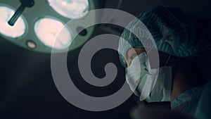 Portrait nurse performing operation holding medical clamp in operating room.