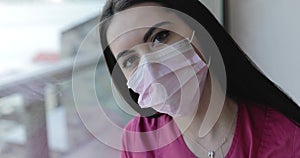 Portrait of nurse in uniform wearing medical mask and looking wearily at camera