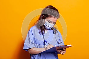 Portrait of nurse wearing face mask and taking notes