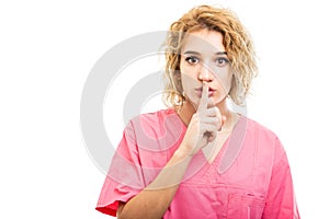 Portrait of nurse wearing pink scrub making silence gesture