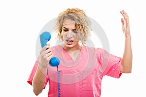 Portrait of nurse wearing pink scrub yelling at telephone receiver