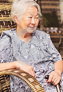 Portrait of a obaasan grandma seated at home, holding a walkin