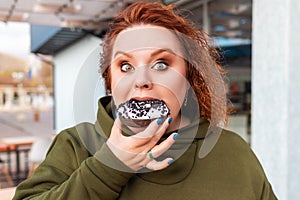 Portrait of obesed amazement woman eating a chocolate donut. The concept of diet and obesity