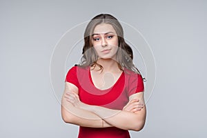 Portrait of offended woman standing with arms crossed on gray background